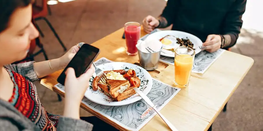 dois amigos sentados a mesa com lanches em um dos restaurantes que aceitam vale-alimentação