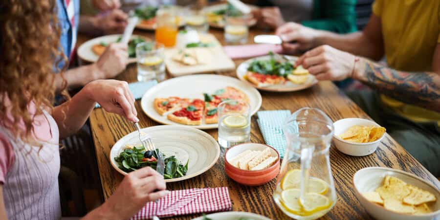 grupo de amigos comendo pizza em restaurante conversando sobre vender vale-refeição