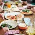 grupo de amigos comendo pizza em restaurante conversando sobre vender vale-refeição