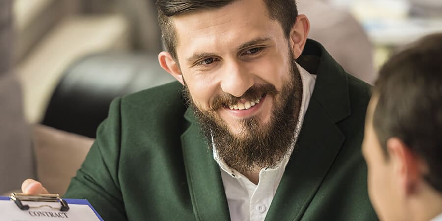 homem sorrindo com um paletó verde em ambiente de trabalho
