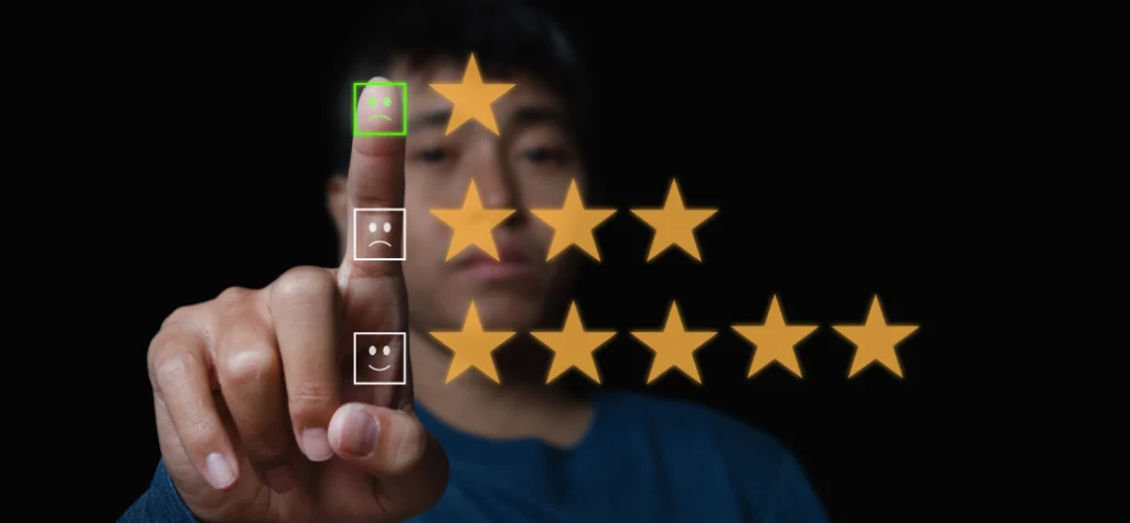 Pessoa desfocada aponta para emojis de avaliação; o emoji triste no topo é selecionado, acima de estrelas amarelas.