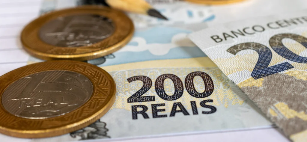 Close-up de uma nota de 200 Reais com moedas de 1 Real em primeiro plano. Dinheiro, finanças e salário.