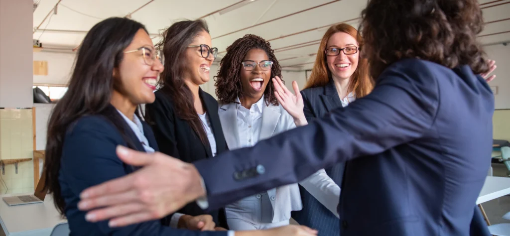 Grupo de mulheres profissionais felizes e surpresas comemorando uma promoção ou conquista no trabalho.