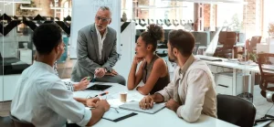 Um grupo diversificado de profissionais envolvidos em uma discussão ao redor de uma mesa de conferência em um ambiente de escritório moderno.
