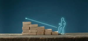 Uma escada de blocos de madeira com o contorno iluminado de uma pessoa subindo, simbolizando progresso e crescimento, contra um fundo azul.