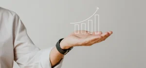 Uma mão aberta com a palma para cima, exibindo um gráfico de linhas com tendências ascendentes, simbolizando crescimento e sucesso nos negócios ou finanças.