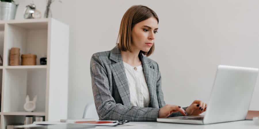 profissional sentada em escritório na frente do notebook esccrevendo carta de recomendação