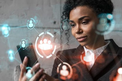 Mulher executiva negra olhando para o celular com projeções digitais de conexão global e ícones de pessoas.
