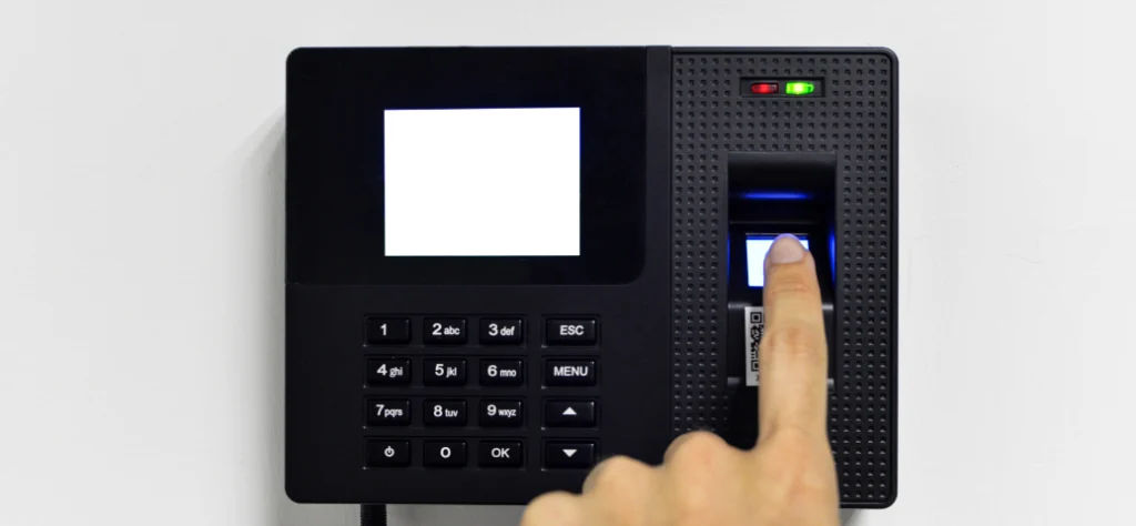 Dedo pressionando o leitor de um relógio de ponto ou controle de acesso biométrico digital no escritório.