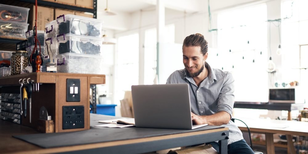 Shot of a young man using a laptop in a workshop