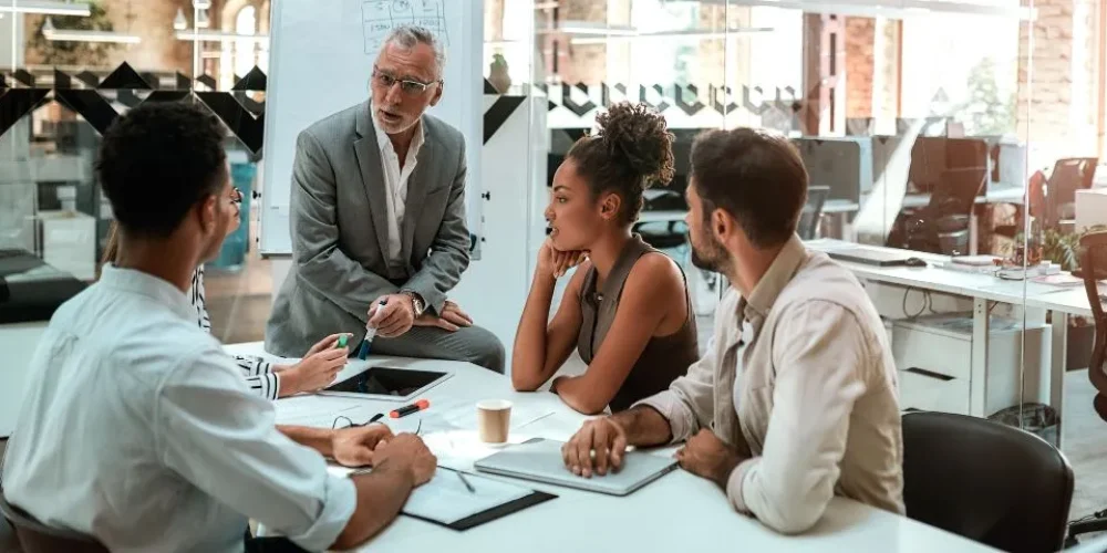 Um grupo diversificado de profissionais envolvidos em uma discussão ao redor de uma mesa de conferência em um ambiente de escritório moderno.