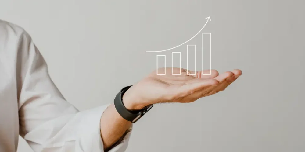 Uma mão aberta com a palma para cima, exibindo um gráfico de linhas com tendências ascendentes, simbolizando crescimento e sucesso nos negócios ou finanças.