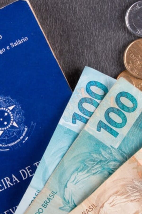 carteira de trabalho e cedulas de reais em cima da mesa representando salário mínimo em 2022